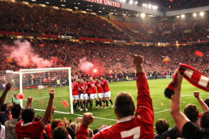 Old Trafford stadium filled with cheering fans celebrating a Manchester United goal