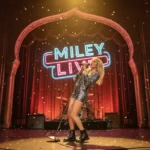 Miley Cyrus on stage at the El Capitan Theatre, wearing the iconic blonde wig