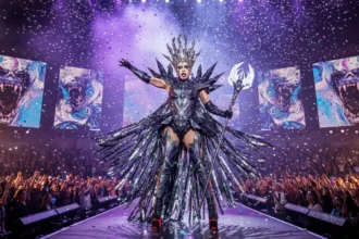 Lady Gaga performing on stage during her Mayhem Ball Tour, wearing a dramatic avant-garde costume.